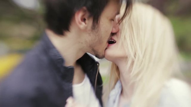 Young European couple hugging and kissing each other. Forever in love. Love is in the air. Portrait, outside shooting, windy weather. Lensbaby, close up view, slow motion.