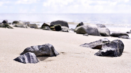 Obraz na płótnie Canvas Pebbles or rocks at the beach. Stones in the sand, beach scene.