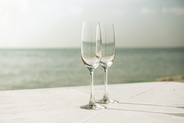  close up of two champagne glasses on beach 