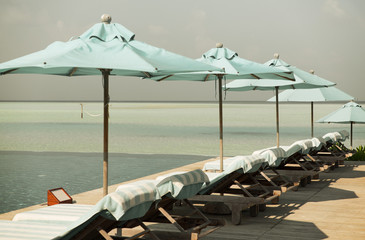 Fototapeta premium parasol and sunbeds by sea on maldives beach