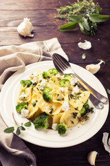 Italian ravioli with goat cheese, broccoli and herbs on old wooden background. Healthy food. Retro style toned