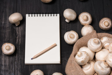 Fresh champignons mushrooms in bag with white note on the wood black table