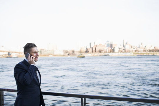 Businessman talking on phone while standing by river