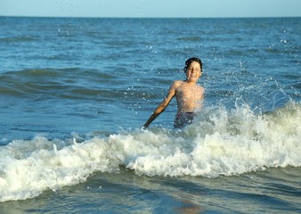 happy boy plays by jumping the waves