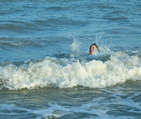 young boy plays by jumping the waves of the sea in summer