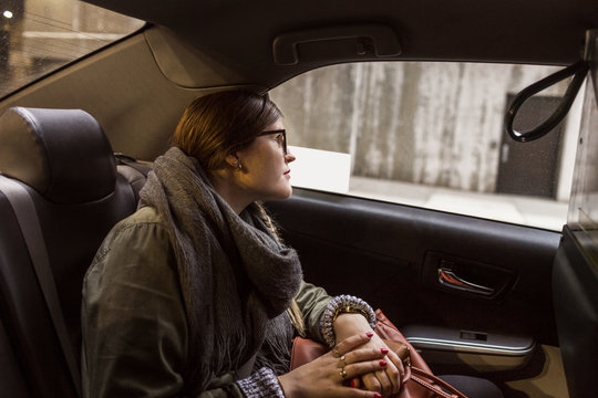 Woman sitting on back seat of car, looking through window
