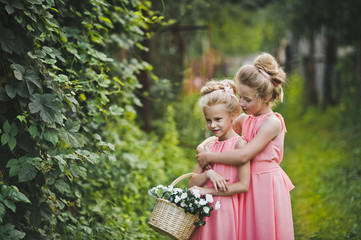 Two girlfriends in a pink dress playing in the garden amongst th