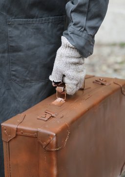 immigrant with old leather suitcase and broken gloves