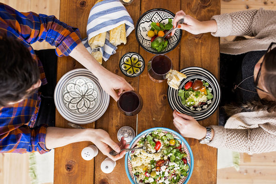 Low section of man and woman having food at wooden table - Powered by Adobe