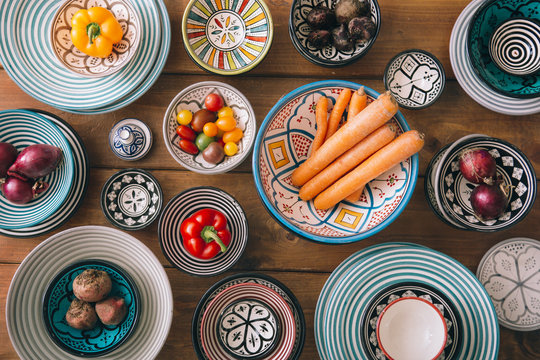 Plates and bowls with vegetables on wooden table