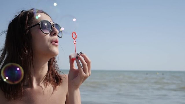 Beautiful young brunette blowing soap bubbles on ocean beach slow-mo 1920X1080 HD video - Female on sea coast playing with air-bubbles slow motion lifestyle 1080p FullHD footage 