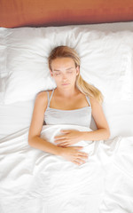Obraz na płótnie Canvas Donna dorme a letto con lenzuola bianche