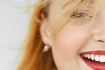 Half face of laughing red-haired woman. Close-up portrait of sunny adorable carroty girl with freckles. Blurry live dynamic photo, free space