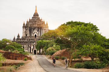 Tourists riding bicycle near pagodas in Bagan on sunset