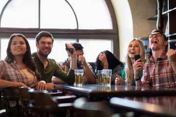 friends with beer watching football at bar or pub