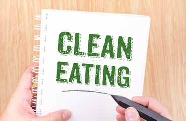 clean eating word on white ring binder notebook with hand holdin