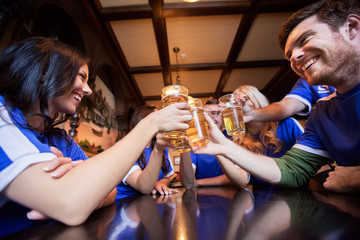 football fans clinking beer glasses at bar or pub