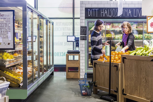 Young woman and man buying oranges in supermarket