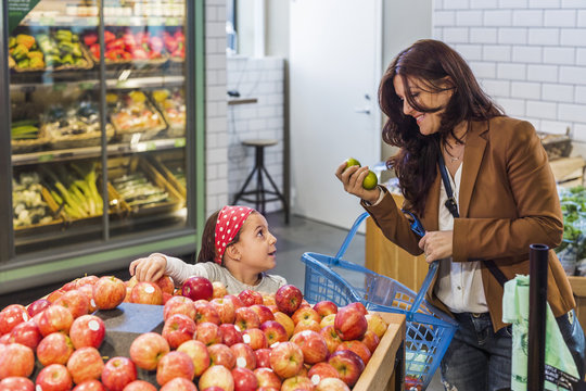 Happy mother and daughter shopping fruits in supermarket