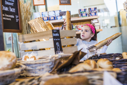 Cute girl buying breads in supermarket