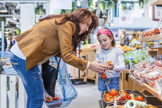 Mother and daughter buying tomatoes in supermarket