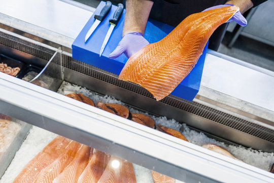 Cropped image of fish vendor holding salmon at supermarket
