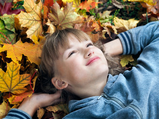 Portrait of a beautiful young teen girl with autumn leaves in the park