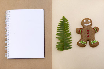Mock up decorated Christmas gingerbread biscuits and blank notepad with craft paper background