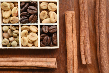 Coffee beans in wooden box and cinnamon on wooden background