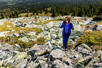 Naklejka na ściany i meble Female is trekking in Mountains among field of stones and rocks.