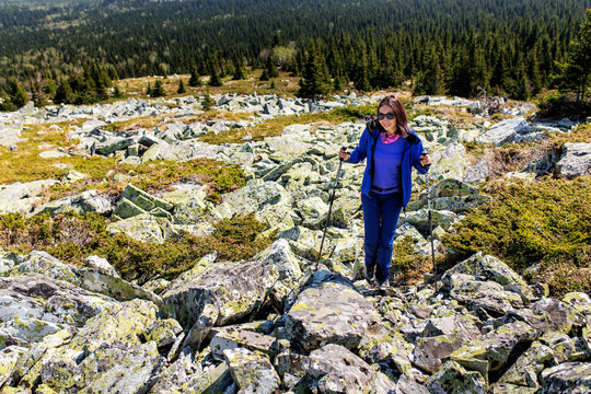 Female is trekking in Mountains among field of stones and rocks.