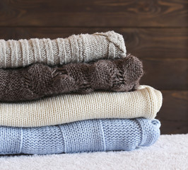 Fototapeta na wymiar Stack of cozy knitted warm sweater on your home background . Sweaters in retro Style. The concept of warm .