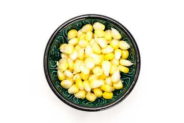 Corn kernels in a bowl, on white background.