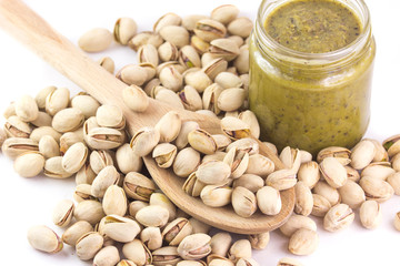Pistacchi in un cucchiaio di legno e un vasetto di pesto