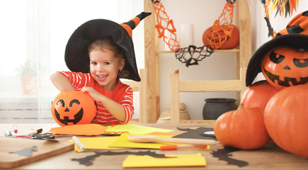 happy laughing child girl in a witches hat eats sweets in Hallow