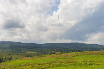 Summer day landscape with road, cloudy sky and small houses. Ukraine, Carpathian.