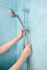 Close-up of human hand adjust the height holder shower head.