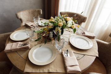 Round wooden dining table decorated with bouquet