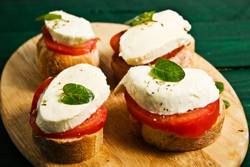 Sandwich from sliced tomatoes, mozzarella, basil and baguette 