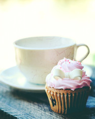 Cup of coffee and cupcake on wooden table