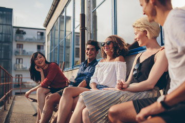 Multiracial group of friends sitting in balcony and smiling - Powered by Adobe