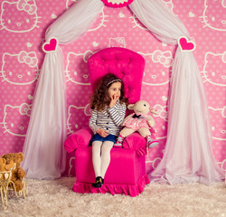 Obraz na płótnie Canvas beautiful little curly girl in a big soft chair