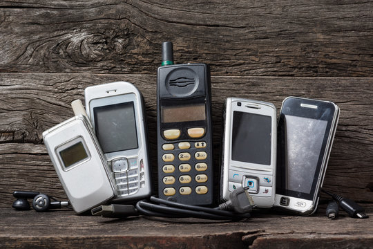 Old And Obsolete Mobile Phone And Accesories On Old Wooden Shelf