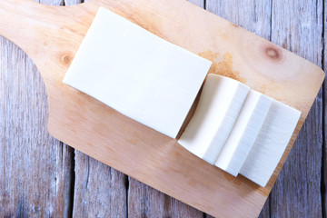 Top view of sliced tofu on a wooden cutting board.