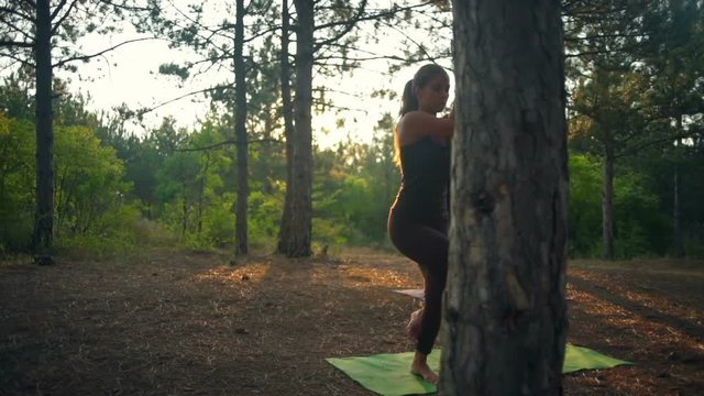 Girls practicing yoga at sunset in forest Garudasana Slow motion