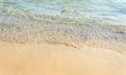 Fototapeta na wymiar wave of blue sea on sandy beach. Close up