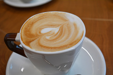 Cup of foamy cappuccino on a wooden table