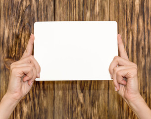 Female hands holding empty sheet on wooden background
