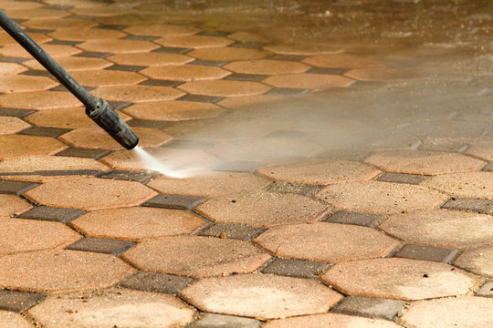Cleaning concrete block floor by high pressure water jet.