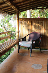 Outdoor patio seating area in bamboo house with brown rattan chair.